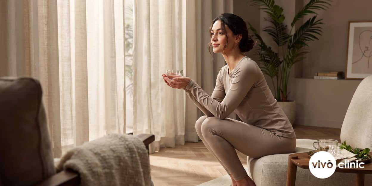 Confident Middle Eastern woman in modest activewear relaxing at home with a cup of tea, conveying restored post-partum comfort and wellbeing, no device, machine or handpiece anywhere in frame