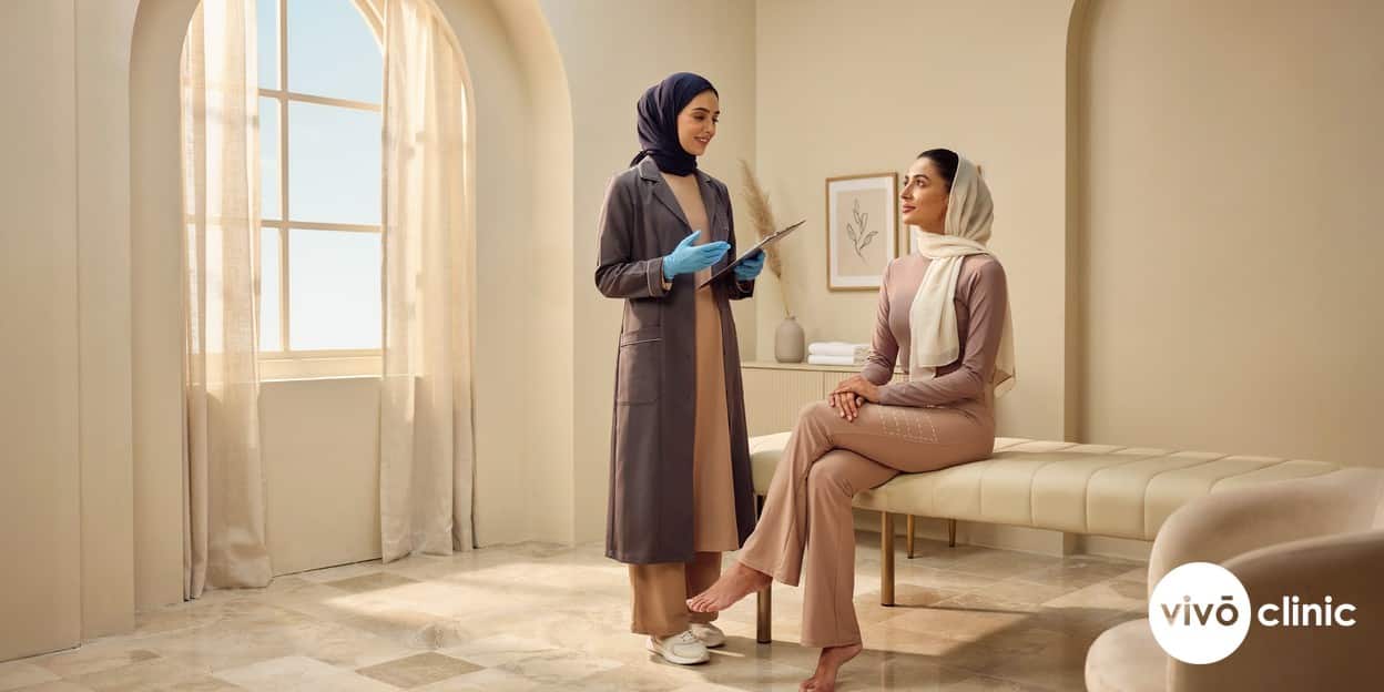 Middle Eastern woman in modest activewear with white cosmetic marking lines on her thigh during a body-contouring consultation at VIVO Clinic Dubai, comparing cellulite reduction with fat freezing