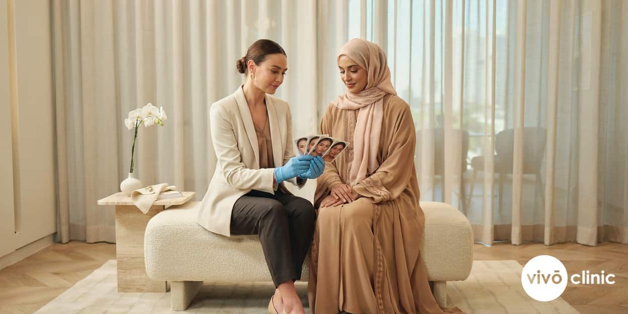 Practitioner in modest attire reviewing before-and-after progress photographs with a Middle Eastern client over three to six months at VIVO Clinic Dubai, showing how fat freezing results develop gradually