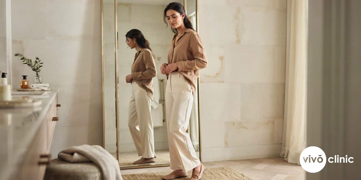 Middle Eastern woman in modest clothing checking her midline in a mirror during the months-long results window after fat freezing at VIVO Clinic Dubai