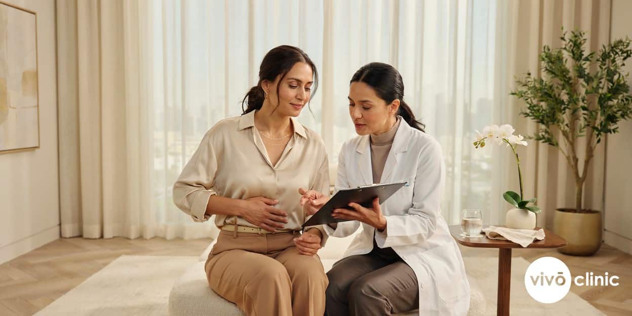 Middle Eastern woman in modest dress reviewing a fat freezing treatment plan with a practitioner who has marked white assessment lines on her abdomen at VIVO Clinic Dubai