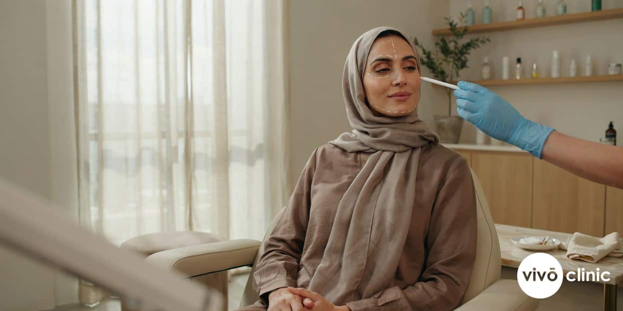 Middle Eastern woman in modest dress with white treatment-planning lines mapped along her jawline during a HIFU facelift consultation at VIVO Clinic Dubai