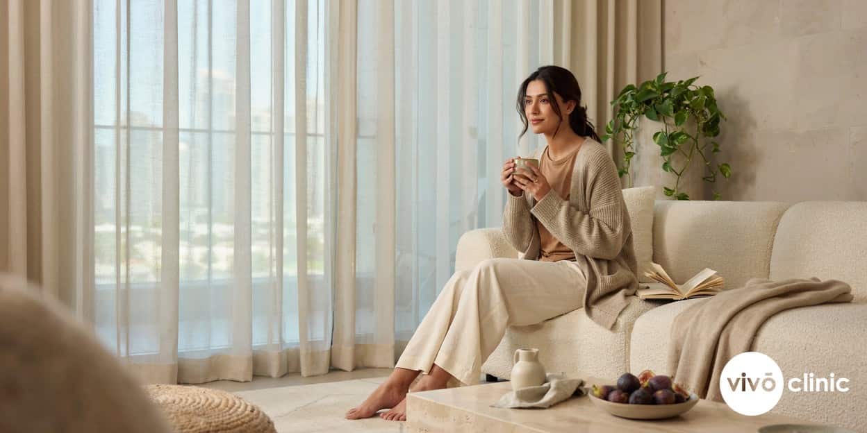 Middle Eastern woman in comfortable modest clothing relaxing calmly at home with a warm drink, conveying easy recovery and minimal downtime after a non-surgical intimate wellness treatment