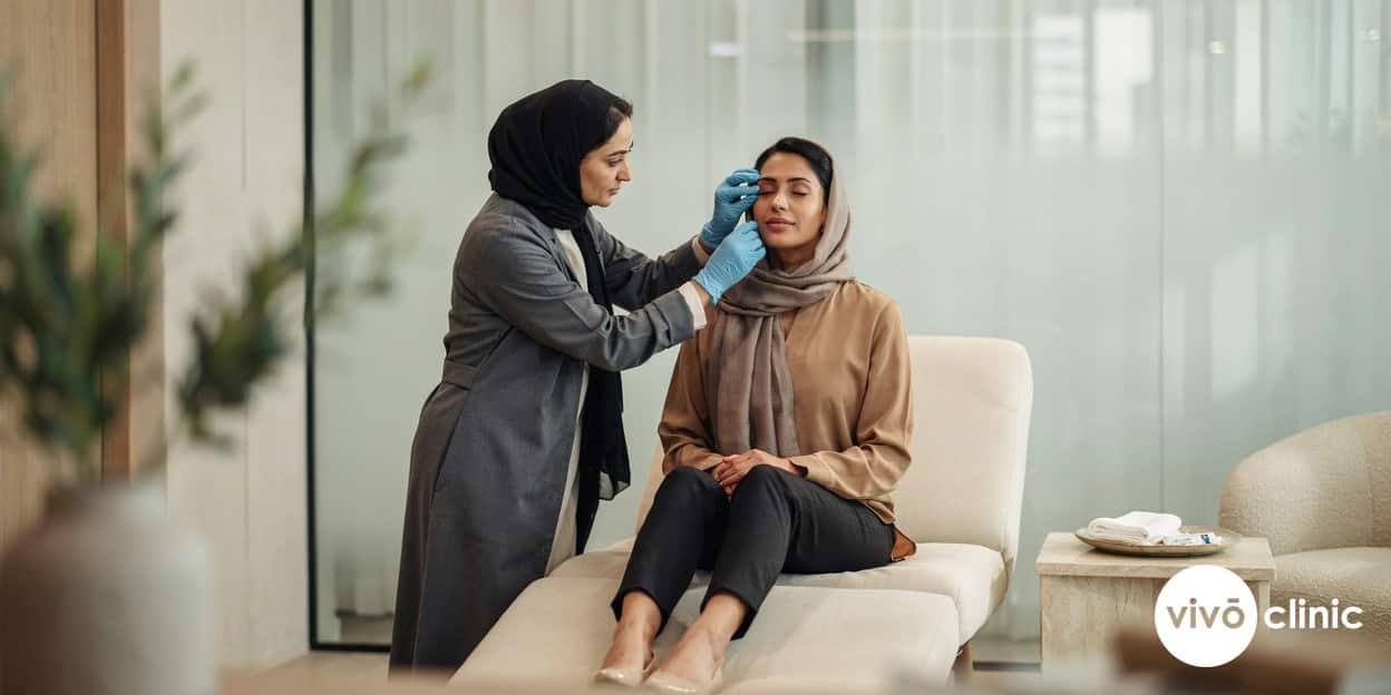 Middle Eastern woman with deeper skin tone during a plasma eye lift suitability consultation at VIVO Clinic Dubai, a practitioner assessing her eyelid skin in modest attire
