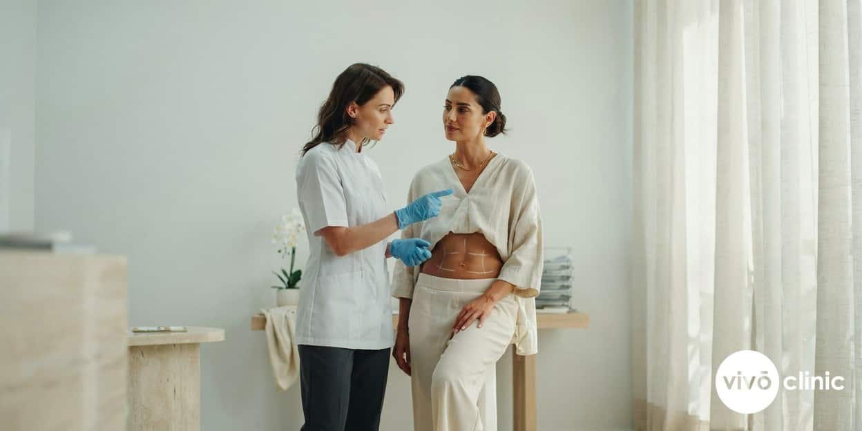 Middle Eastern woman in modest dress with white cosmetic marking lines on her abdomen during an ultrasound cavitation body-contouring consultation at VIVO Clinic Dubai