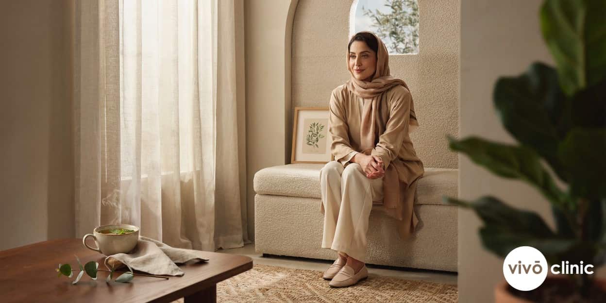 Middle Eastern woman in modest clothing sitting comfortably in a calm, private consultation room, illustrating an open and unhurried conversation about intimate wellness