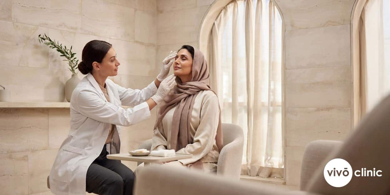 Practitioner in modest attire using a gloved hand to gently examine the healing skin around a Middle Eastern woman’s eye during a plasma eye lift follow-up at VIVO Clinic Dubai, no device or handpiece in frame