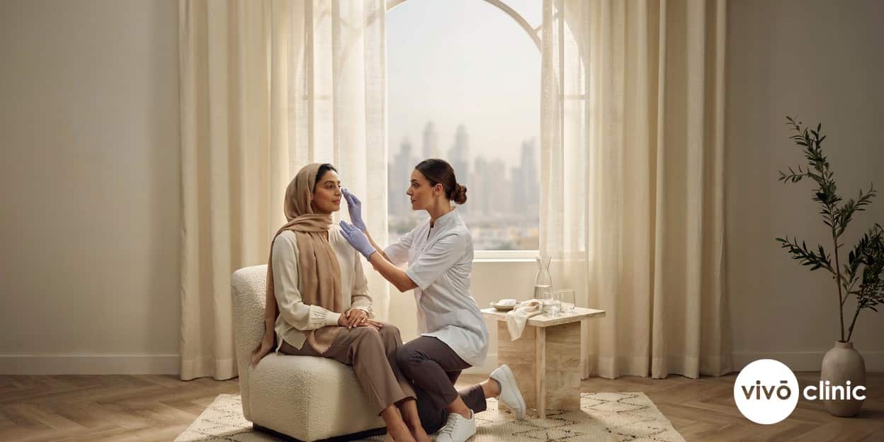 Middle Eastern woman in a consultation with a practitioner who is gently examining the skin around her eyes before a plasma eye lift at VIVO Clinic Dubai, discussing risks and safety