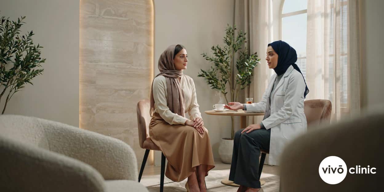 Middle Eastern woman in modest dress in conversation with a practitioner during a thorough RF facelift safety consultation at VIVO Clinic Dubai, no device or machine in frame