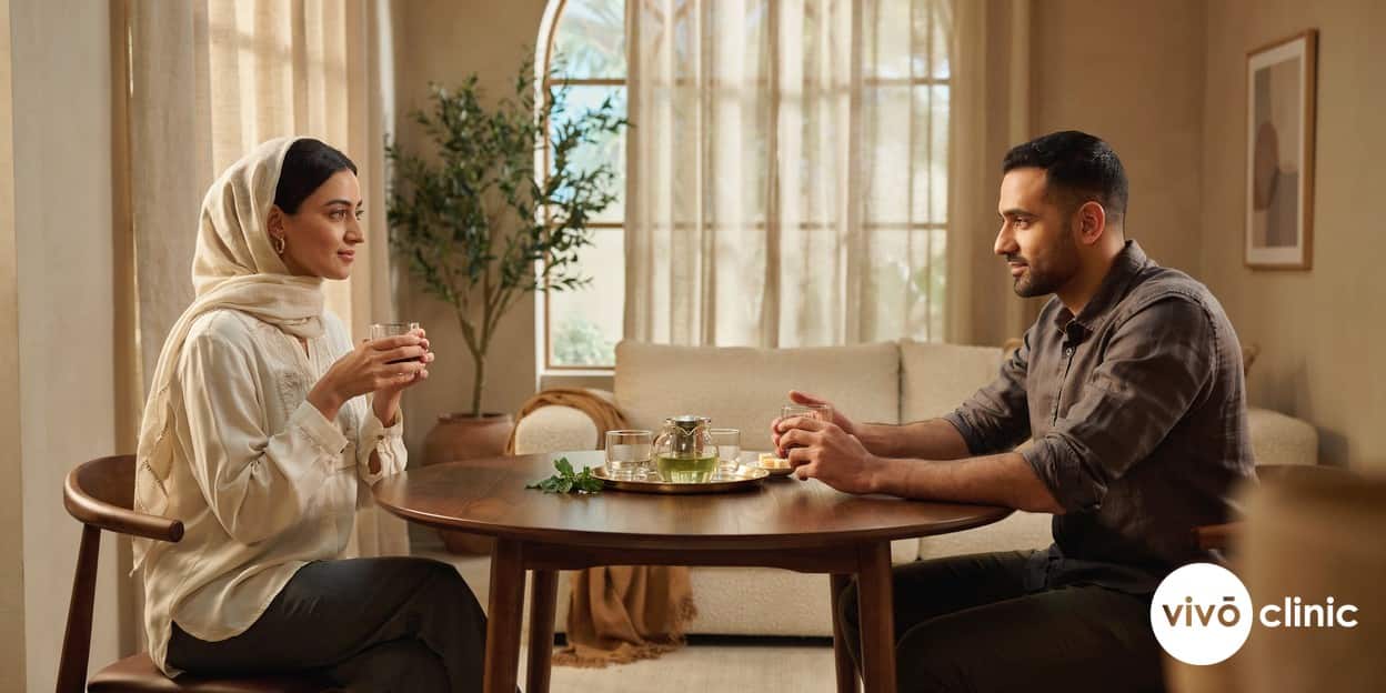 Middle Eastern couple talking warmly together over tea at home in Dubai, illustrating an open conversation about vaginal tightening treatment