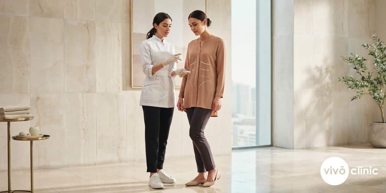 Middle Eastern woman in modest clothing during a body contouring consultation with white cosmetic marking lines on her abdomen at VIVO Clinic Dubai