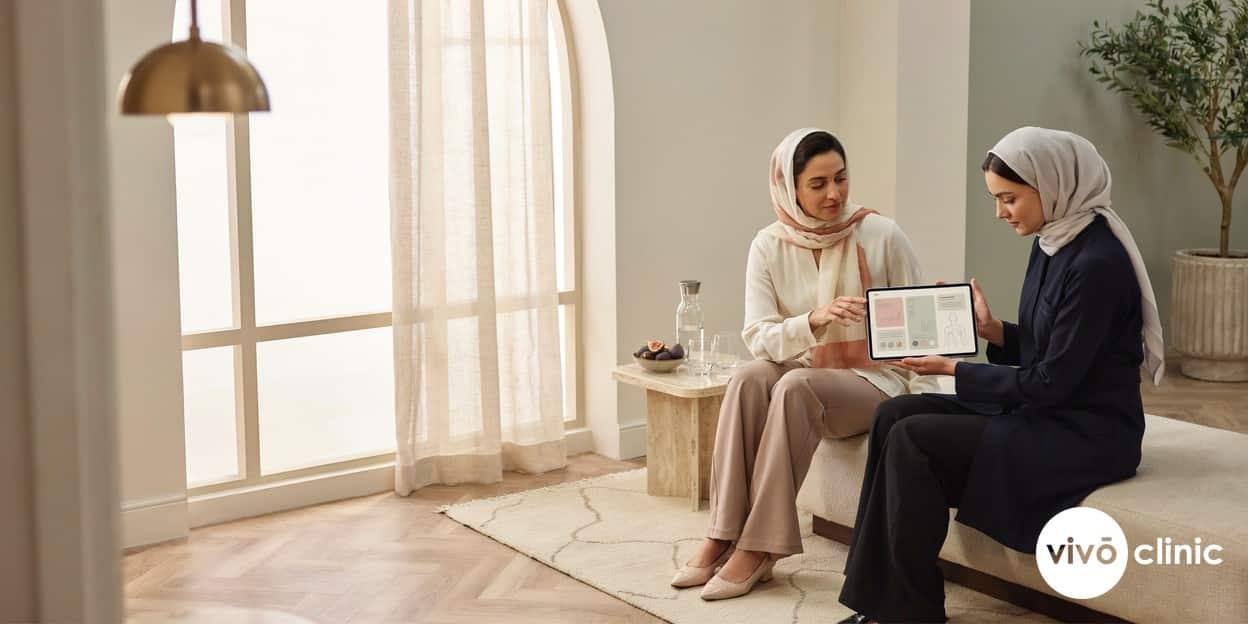 Middle Eastern woman in modest dress during an evidence-led aesthetic consultation at VIVO Clinic Dubai, reviewing a personalised treatment plan on a tablet