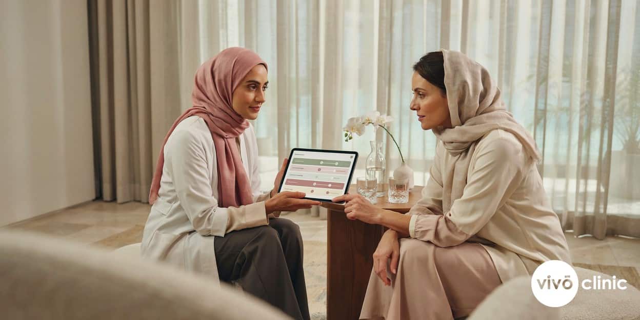 Middle Eastern practitioner in modest attire reviewing a tailored, multi-session treatment plan on a tablet with a female patient at VIVO Clinic Dubai