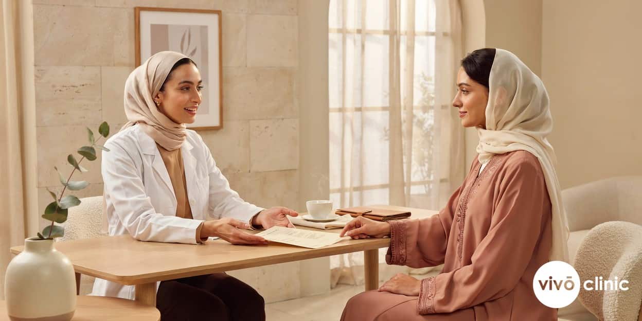 Middle Eastern practitioner and woman in modest dress smiling as they review a treatment plan together at VIVO Clinic Dubai