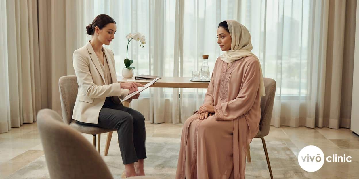 Practitioner in modest attire reviewing a multi-treatment session plan with a Middle Eastern woman at VIVO Clinic Dubai, mapping which non-surgical treatments can be combined in one appointment